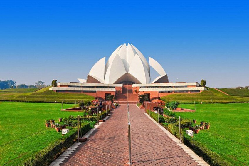 A large white lotus-shaped building with a brick pathway leading to it. 5