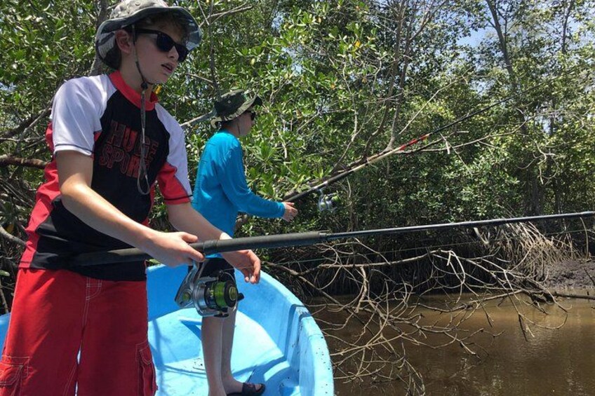 Two people fishing on a boat in a mangrove area. 2