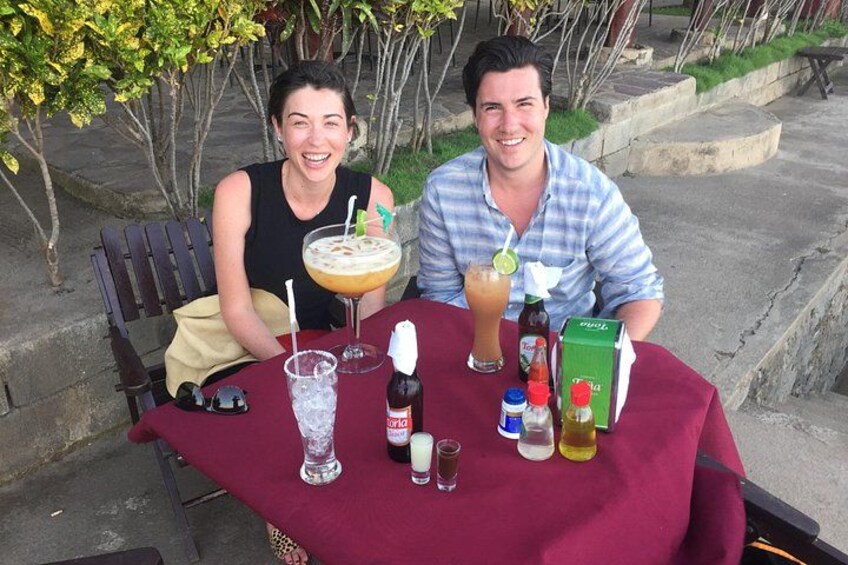Two people seated at an outdoor table with drinks and condiments. 5