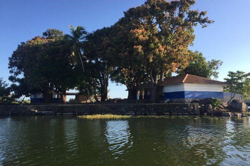 A calm lake with a stone wall, trees, and a building with a blue and white facade. 4