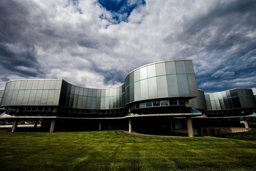 A modern building with curved architecture and a grassy foreground. 1