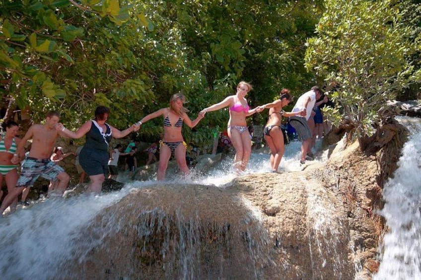 Menschen springen in einen Wasserfall in einer bewaldeten Gegend. 4