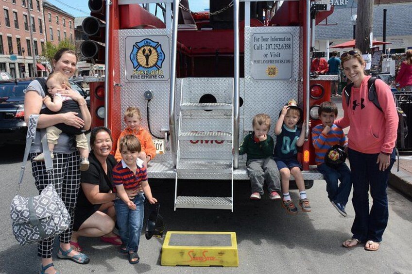 A fire truck with children and adults posing in front of it. 2