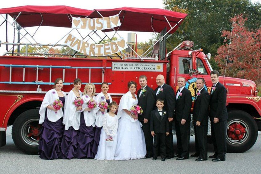A group of people in front of a red fire truck with a 'Just Married' sign. 3