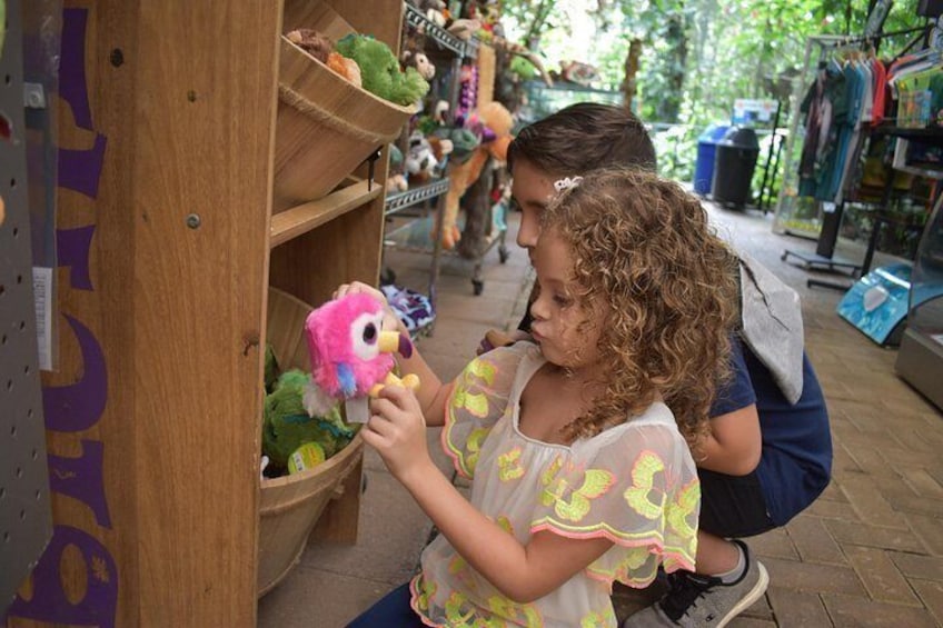 A person holding a toy bird, with shelves of stuffed animals in the background. 3