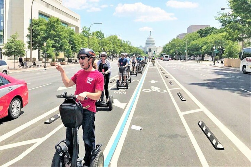 A person riding a Segway on a city street with a clear view of the Capitol building in the background. 1
