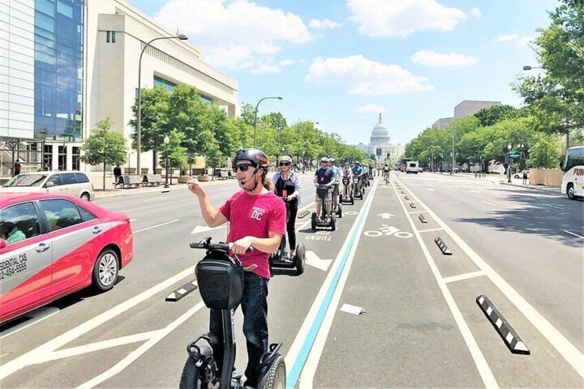 Una persona en un Segway en un carril bici, con el edificio del Capitolio al fondo. 2