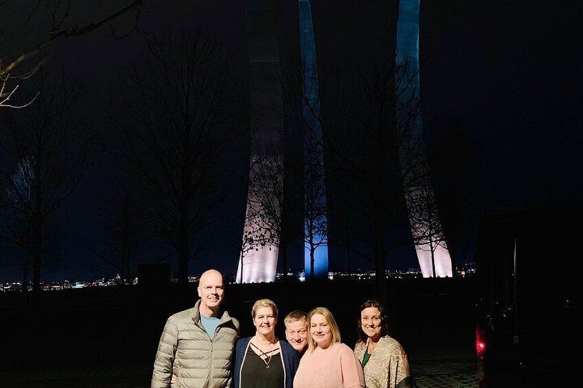 A group of people standing in front of illuminated towers at night. 4
