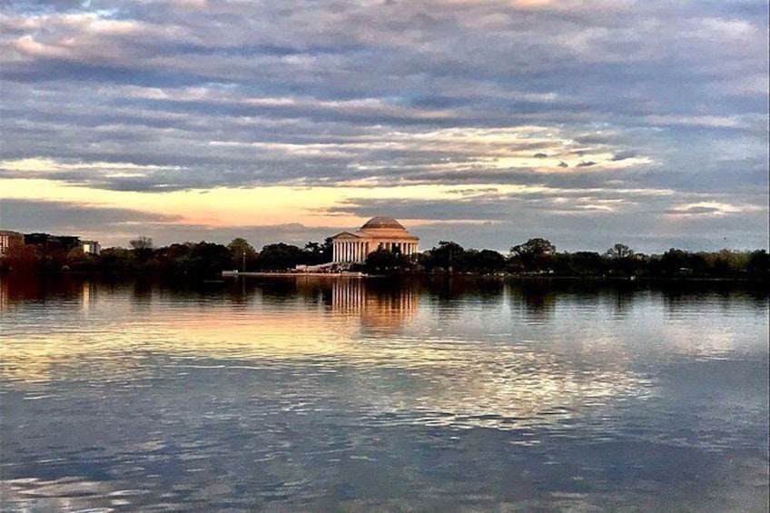A body of water reflecting a building with columns and a dome, under a cloudy sky. 3