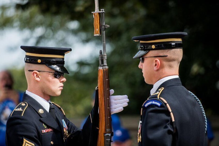 Two military personnel in uniform with rifles, standing outdoors. 1