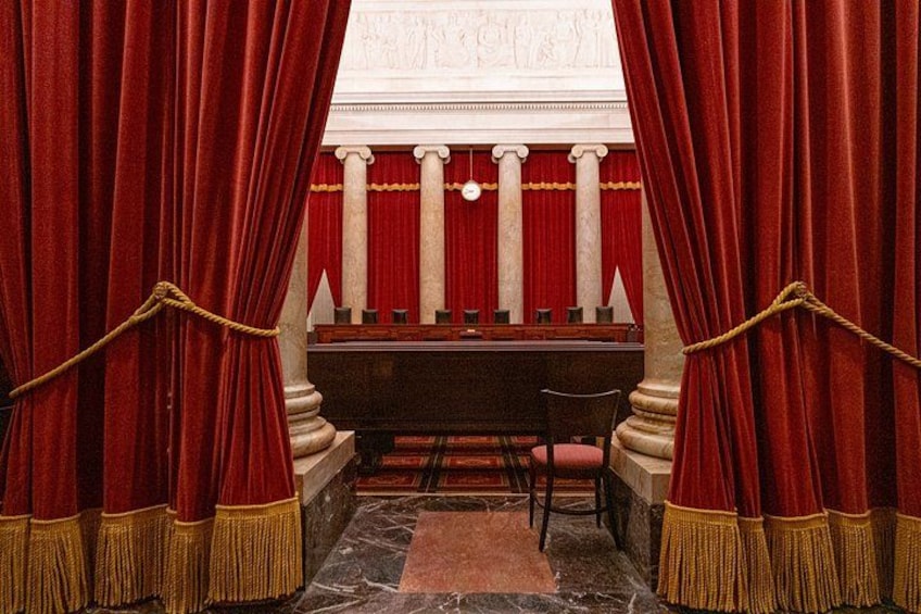 A courtroom with red curtains, a judge's bench, and a witness stand. 4