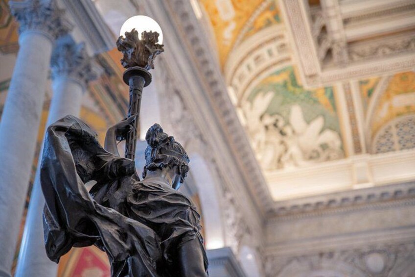 A statue with a spherical object on top, set against a backdrop of ornate architectural details and columns. 4