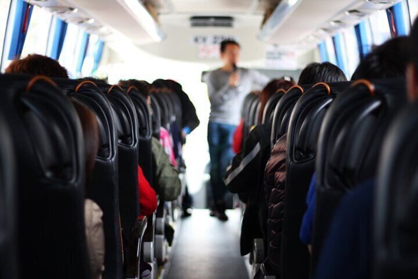Insidan av en buss med rader av säten och passagerare. 3