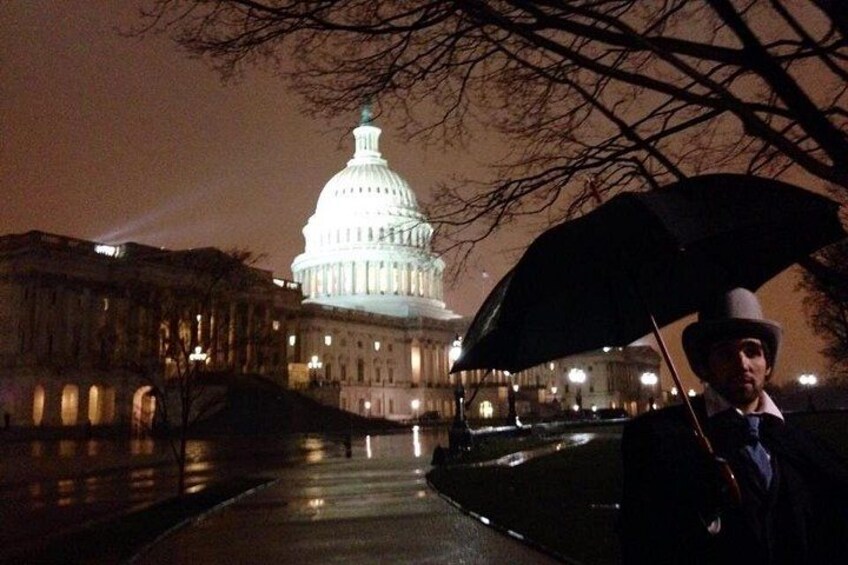 A person holding an umbrella in front of a brightly lit capitol building at night. 2