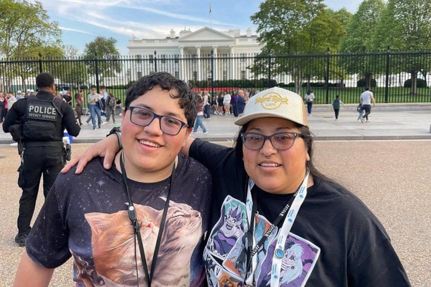 Two people with a large building and a fence in the background. 2