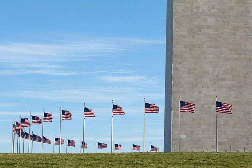En række amerikanske flag på flagstænger foran en stor betonbygning. 5