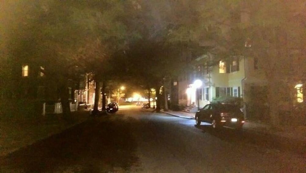 En svagt oplyst gade om natten med parkerede biler og huse på begge sider. 5