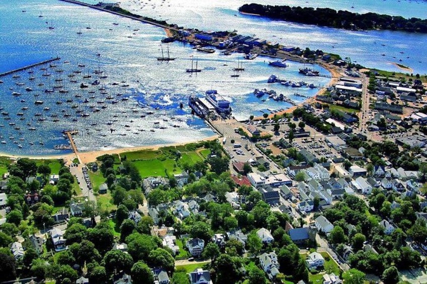 Een kustplaatsje met tal van boten afgemeerd langs de kustlijn, een jachthaven en woonwijken met huizen en groen. 3