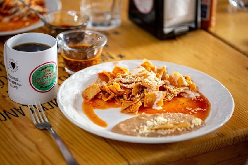 A plate of pasta with sauce, a cup of coffee, and a glass of water on a wooden table. 4