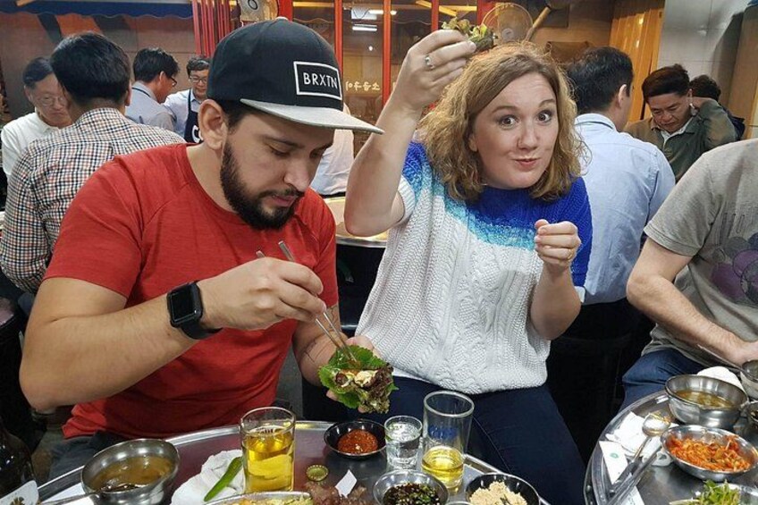 Two people dining at a restaurant with various dishes and drinks on the table. 1