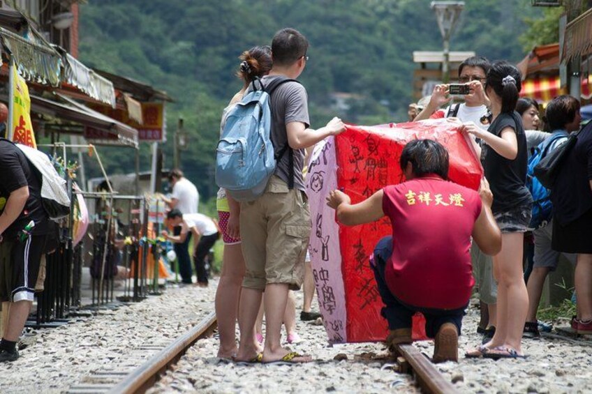 Un grupo de personas de pie sobre vías de tren, algunas sosteniendo un gran cartel rojo con caracteres chinos. 2