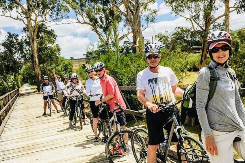 A group of cyclists on a wooden bridge surrounded by trees. 3