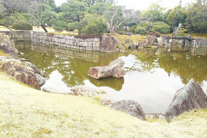 A pond with rocks and trees in a park. 2
