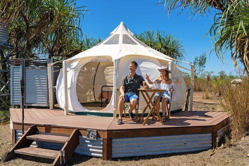 A couple sitting at a table under a tent on a wooden deck. 2