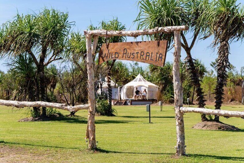 A sign reading 'WILD Australia' in a grassy area with trees and a white structure in the background. 2
