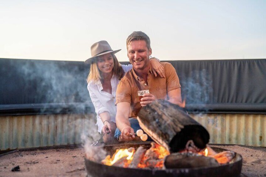 Two people cooking outdoors with a campfire. 3
