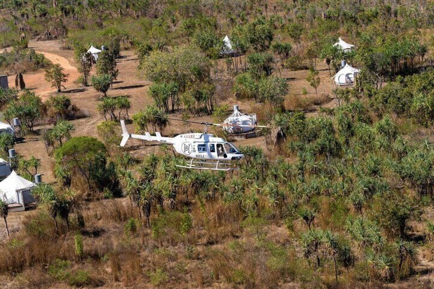A helicopter in a remote area with sparse vegetation and small structures. 5