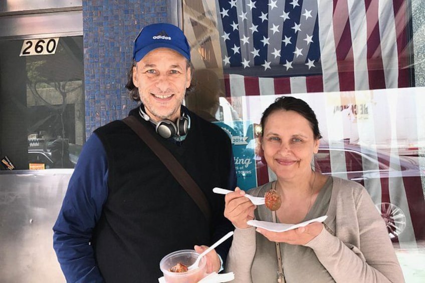 A man and a woman in front of an American flag, with a building number 260 visible. 5