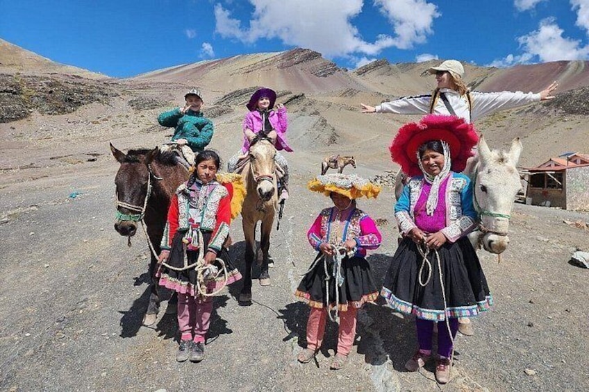 Un grupo de personas vestidas con atuendos tradicionales junto a caballos y un burro en un paisaje montañoso. 3
