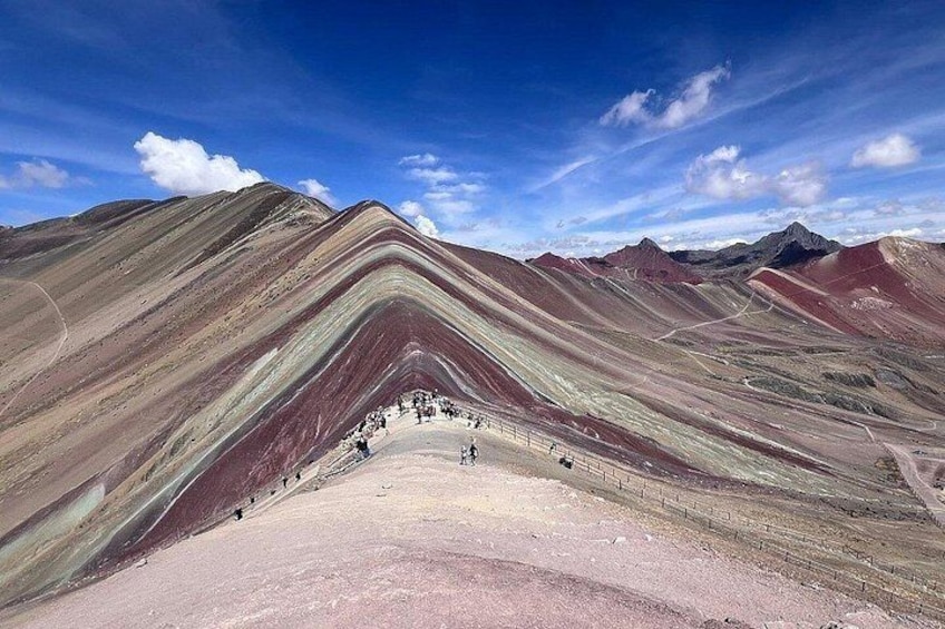 Paisaje montañoso con formaciones rocosas escalonadas y un grupo de personas en la base. 4
