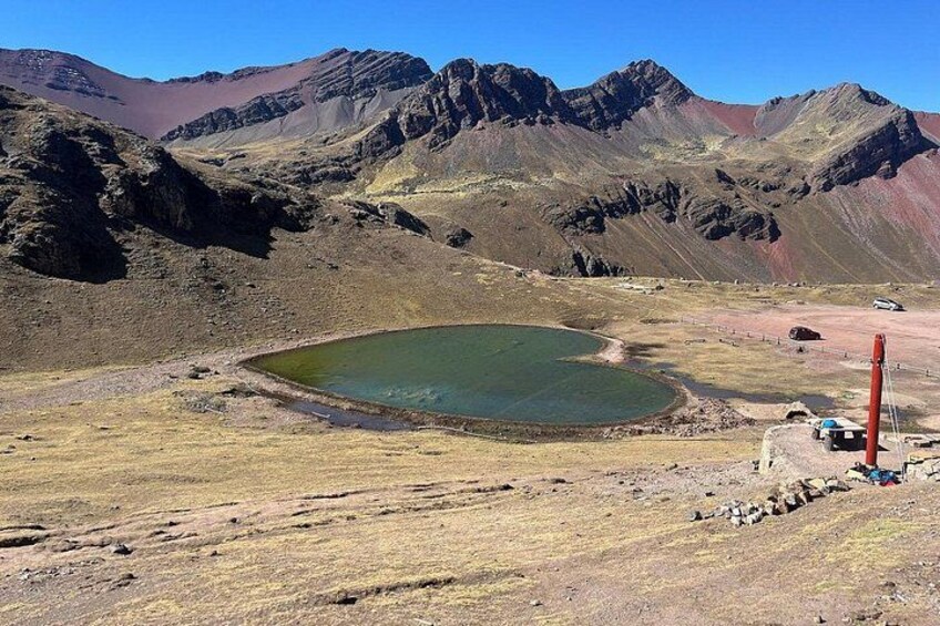 Eine Berglandschaft mit einem kleinen Gewässer, felsigem Gelände und einem roten Pfahl. 4