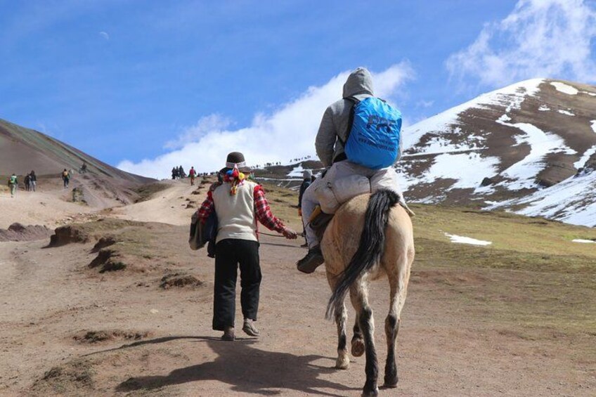 A person riding a horse on a dirt trail with a mountainous landscape in the background. 4