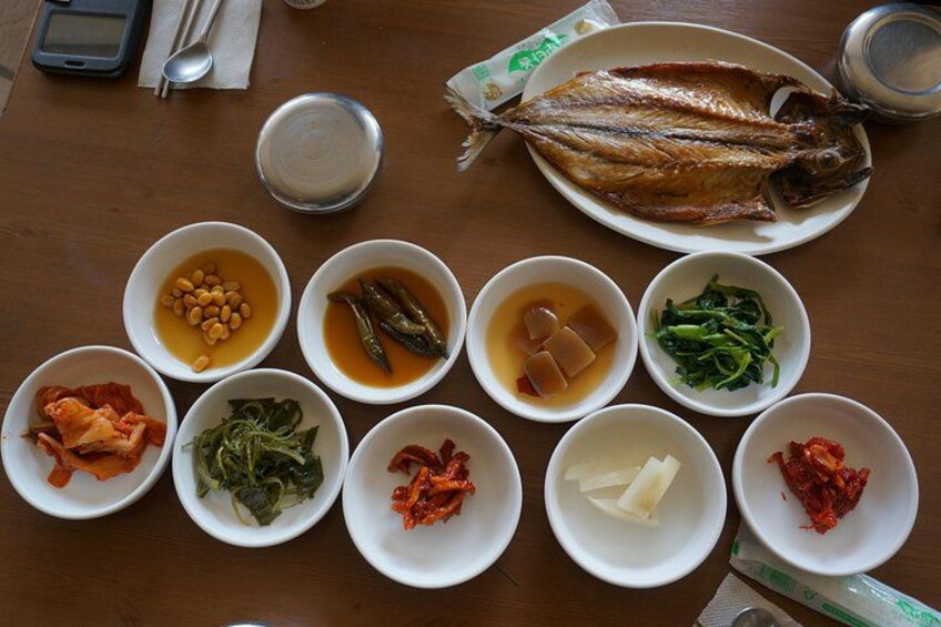 A variety of dishes including a whole fish, bean soup, and several small bowls of side dishes. 3