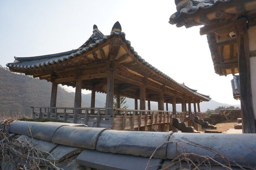 A traditional Korean pavilion with a tiled roof, wooden beams, and a stone base. 4