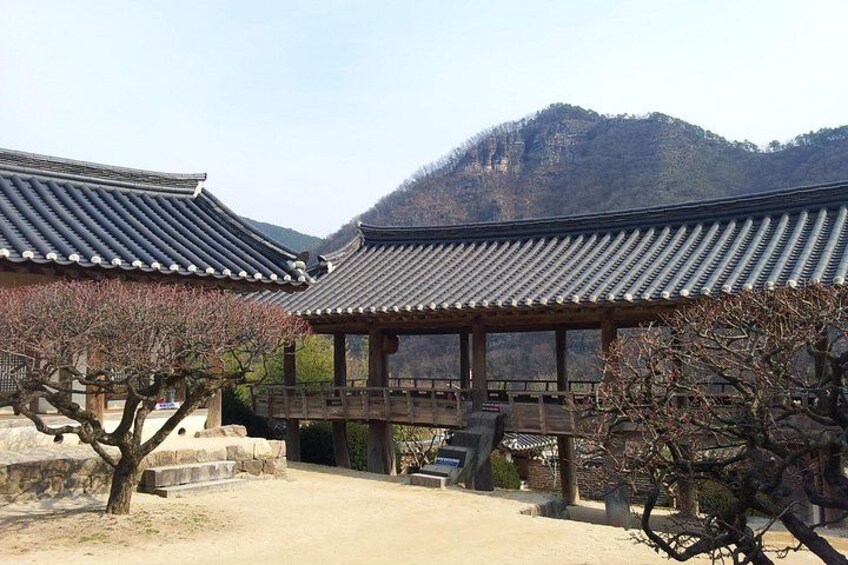 Traditional Korean architecture with tiled roofs, a wooden pavilion, and a mountainous backdrop. 3