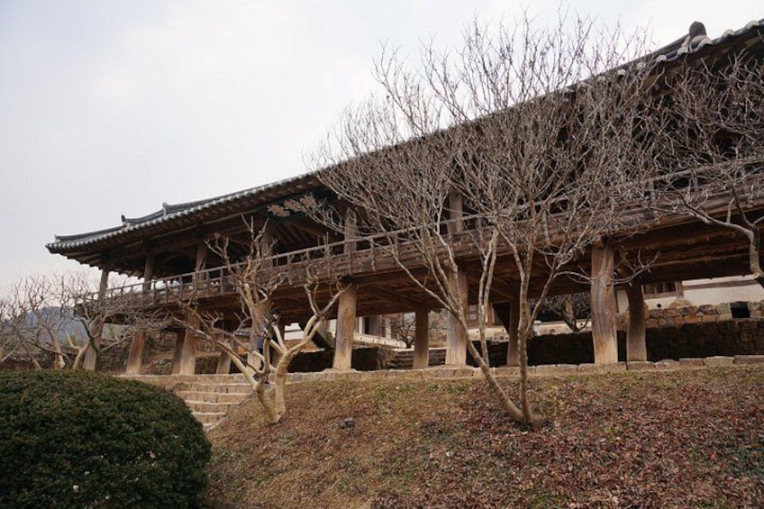 A traditional Korean building with a wooden structure, a stone base, and leafless trees. 5