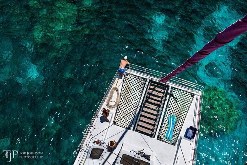 A boat with a person standing at the bow, a netted area, and clear blue water. 2