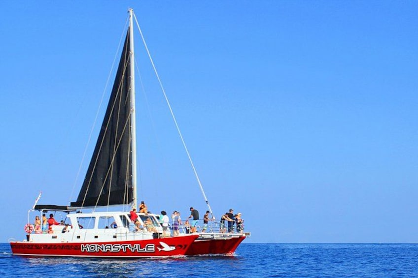 A red and white boat with the name 'Konastyle' on the side, sailing on blue water. 3