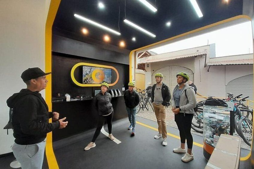 A group of people in a modern indoor space with bicycles and a wall-mounted artwork. 3