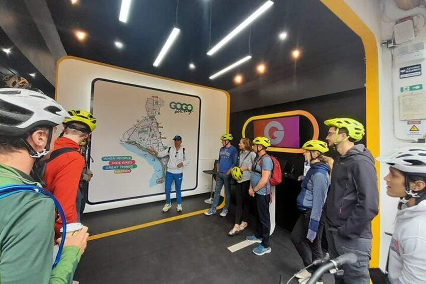 A group of people in helmets, standing in a room with a large map and a sign that reads 'Coco Race.' 1
