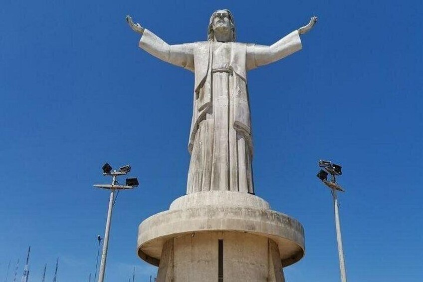 Una estatua grande con los brazos extendidos, sobre un pedestal circular, con faroles a cada lado. 4