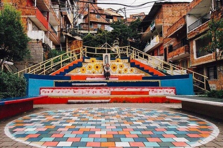 A colorful staircase with a patterned floor leading up to a building. 1