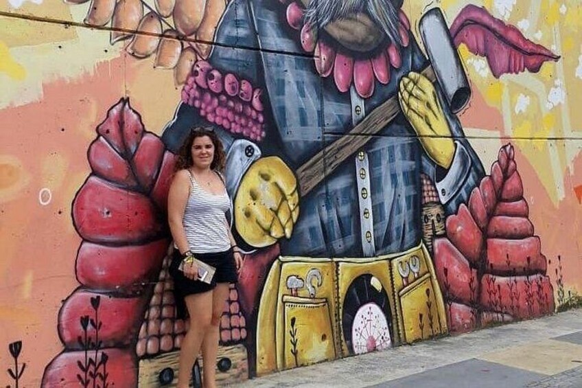 A person standing in front of a colorful mural with a large face and abstract shapes. 5