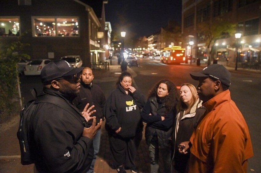 A group of people standing on a street at night. 2