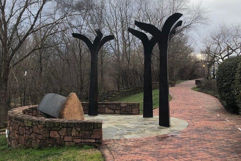 A paved pathway with stone walls and metal sculptures. 4
