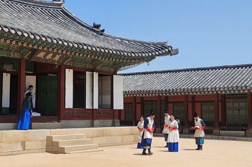 Un edificio tradicional coreano con techo de tejas y una persona vestida de azul frente a él. 5